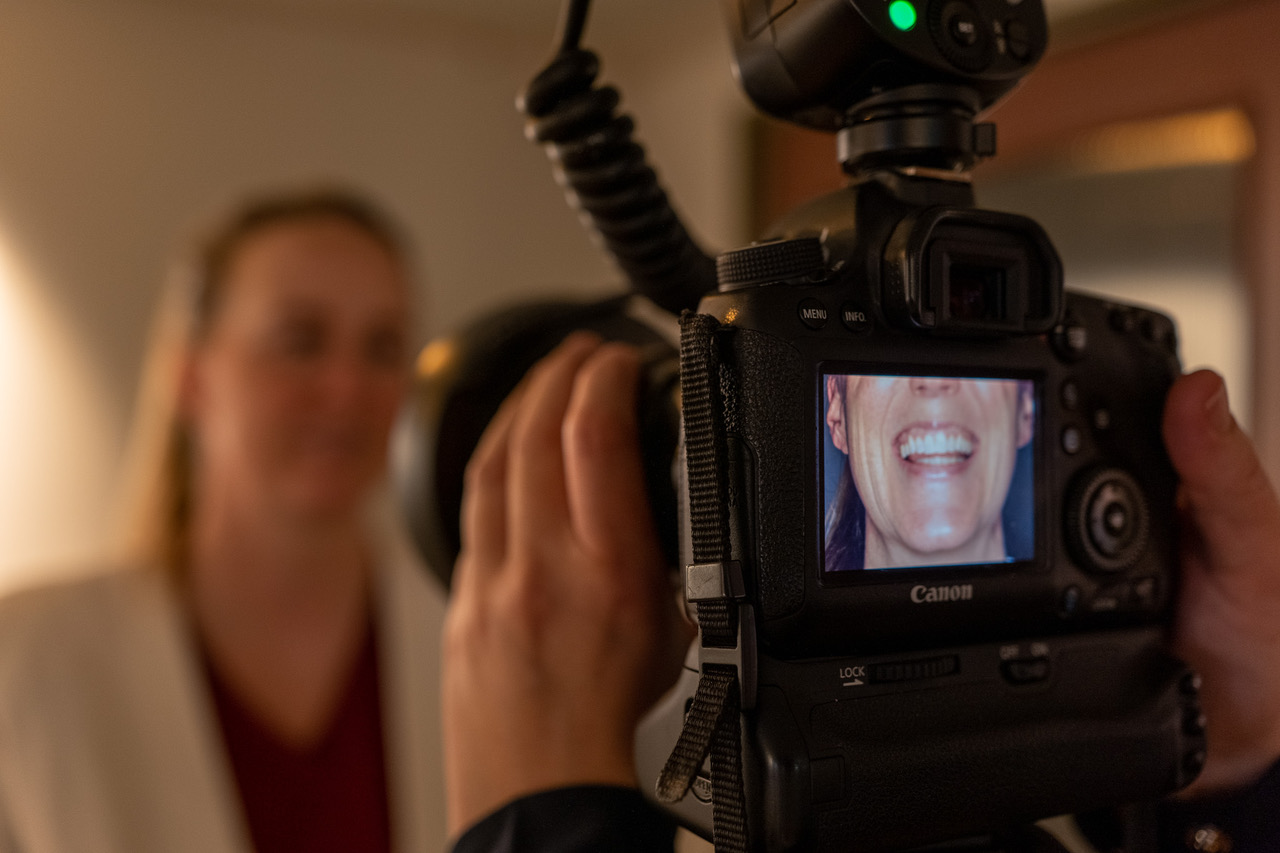Kamera med makroblits fotograferer et smil, med smilet vist på kameraskjermen og pasienten uskarpt i bakgrunnen